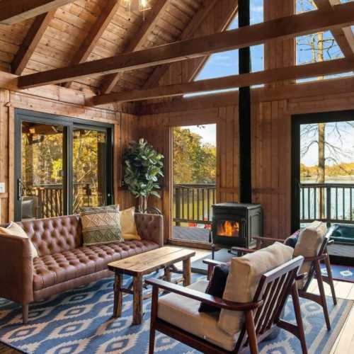 Lovely great room affords beautiful views of the lake, opens on to the screened porch (left) and the hot  tub (center), has a wood burning stove and a 50" Amazon Fire TV