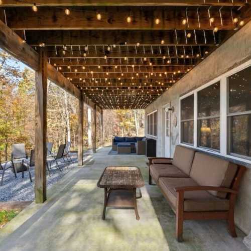 The patio overlooks a lush landscape with vibrant fall foliage, offering a serene and picturesque setting. Including lounge chairs and a sofa, ensure comfort for gatherings or solo relaxation.